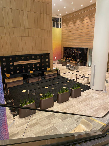 Modern hotel lobby with wooden walls, elegant seating, and planters on a marble floor.