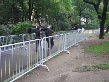 Metal security barriers in a park, used for crowd control, with police officers nearby.