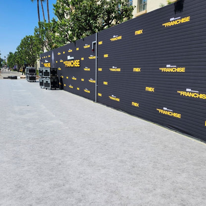 Backdrop for HBO's 'The Franchise', featuring a black wall with yellow logos, set on a gray surface.