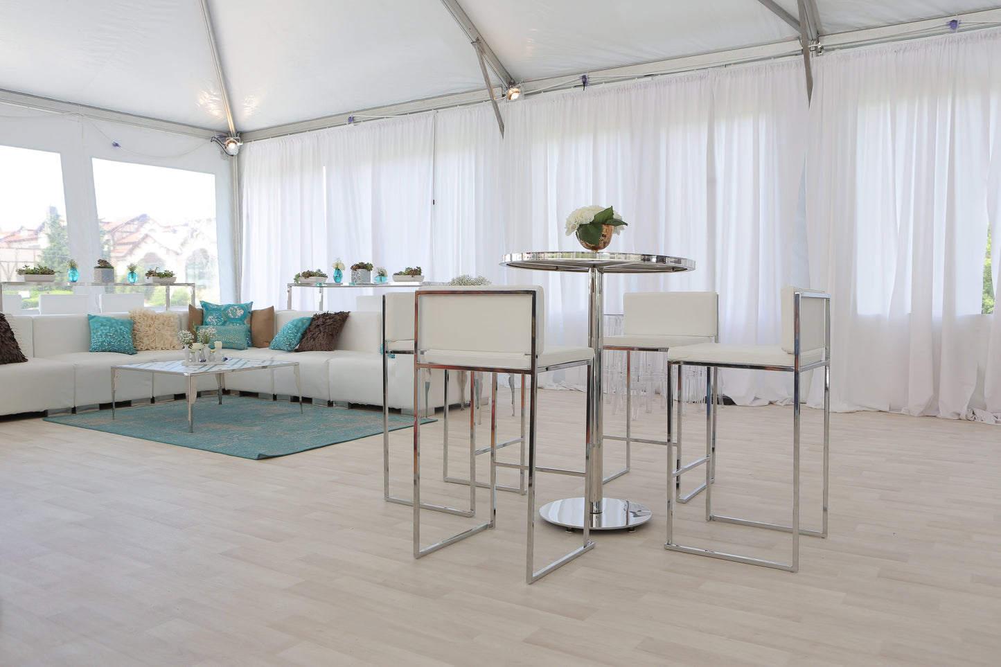 Modern white bar stools and table with chrome accents in a stylish event space.