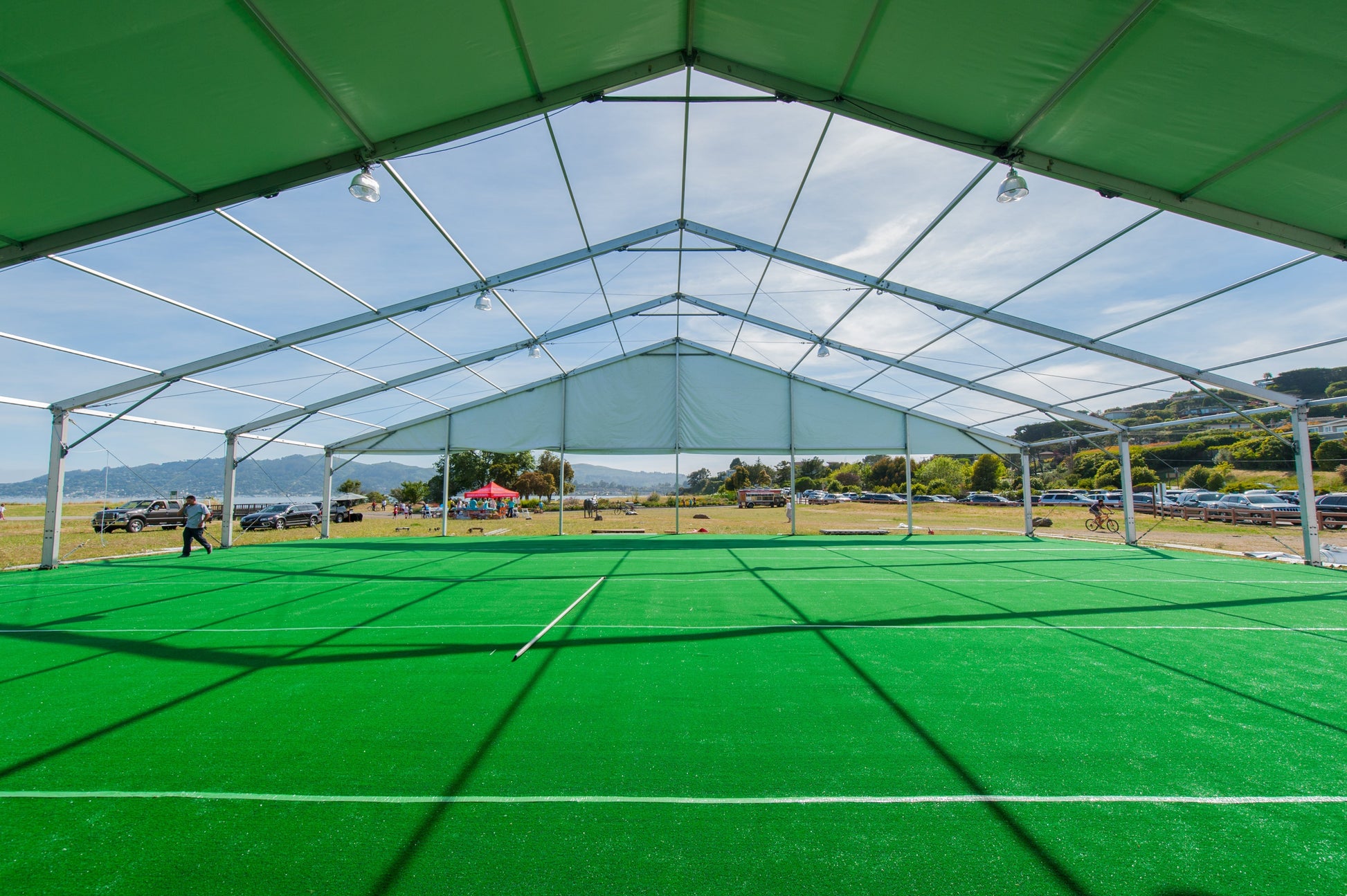 Large outdoor tent with a green turf floor, ideal for sports events and gatherings.