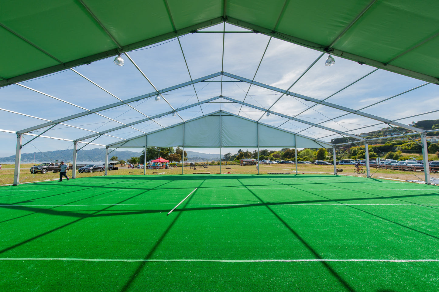 Spacious outdoor event tent with green artificial turf flooring, ideal for sports and gatherings.