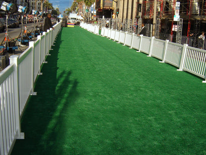 Green artificial turf with white fencing, ideal for events and red carpets, providing a stylish outdoor path.