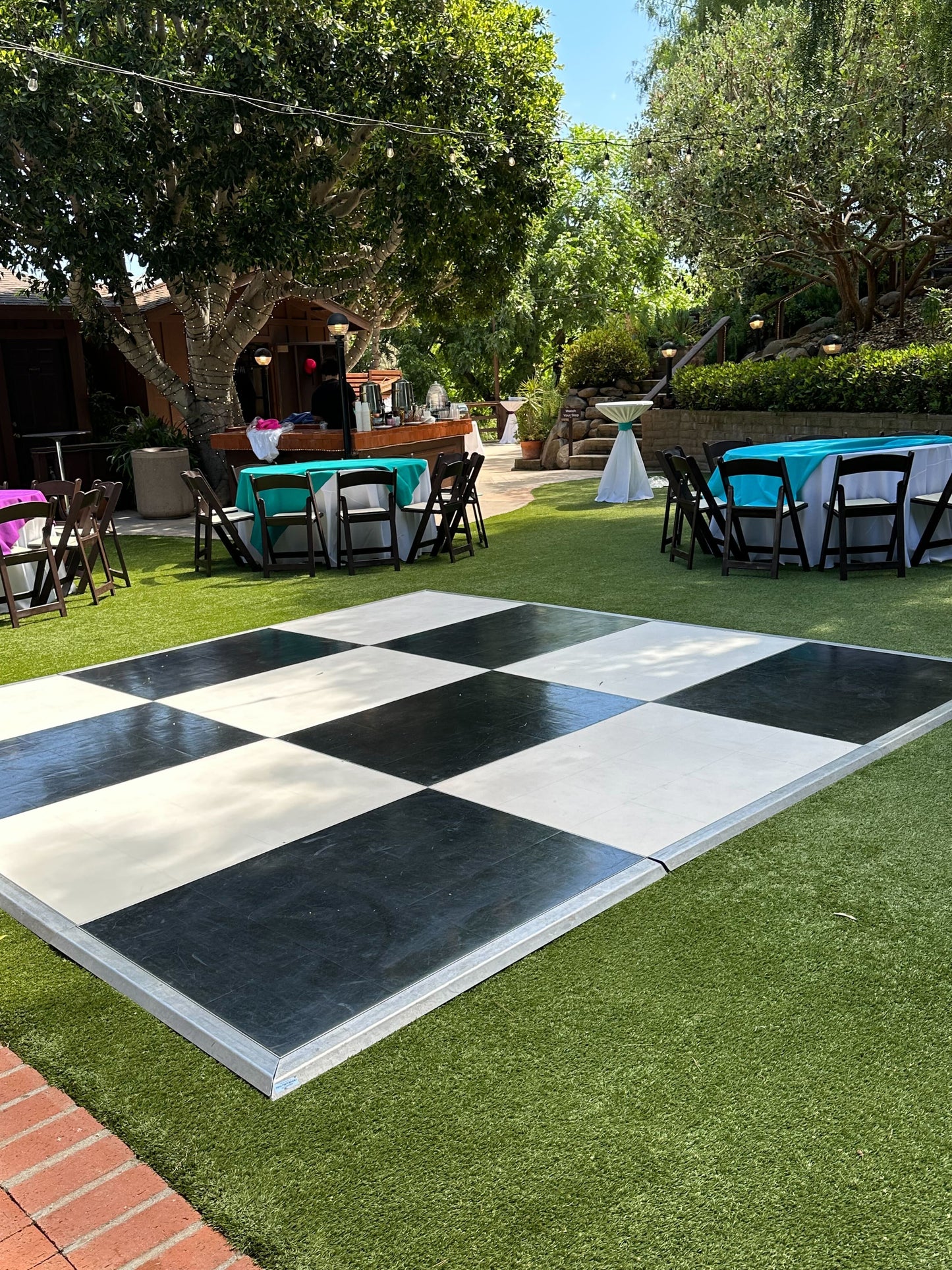 Large outdoor checkered dance floor, black and white tiles on artificial grass, perfect for events.