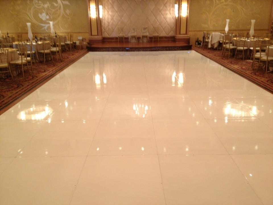Shiny white dance floor in an elegant banquet hall with golden chairs and stylish decor.