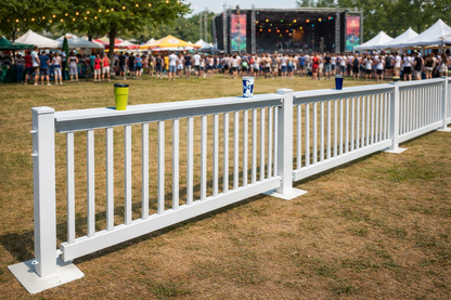 White outdoor festival railing with space for drinks, set against a crowd at a music event.