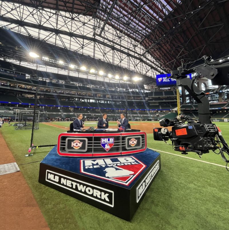 MLB Network studio set on baseball field with analysts discussing game, featuring modern design and bright lighting.