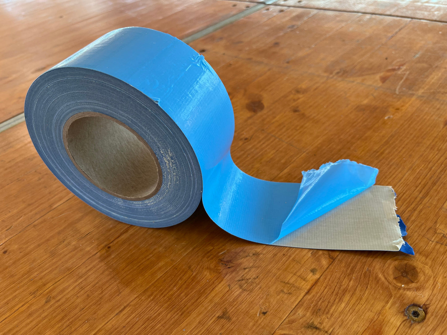 Blue duct tape roll with a tear-off edge, ideal for repairs and crafting projects.