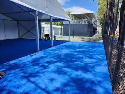 Bright blue outdoor carpet under a large tent, ideal for events and gatherings.