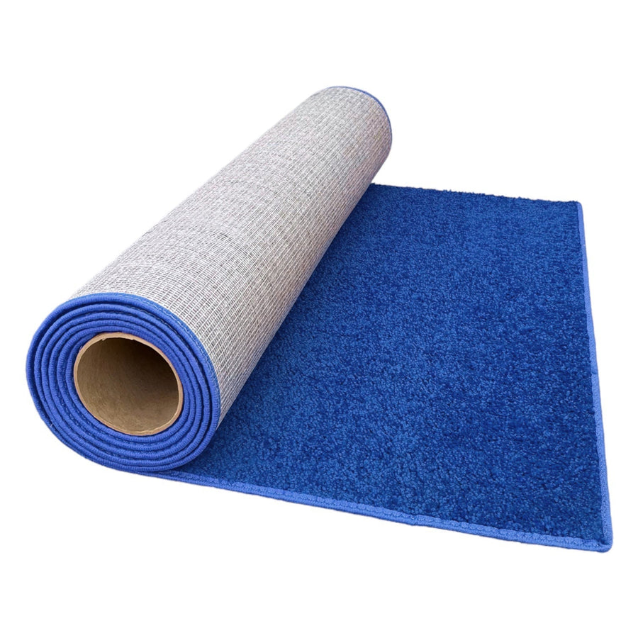 Blue plush area rug with non-slip backing, rolled and partially unrolled for display.