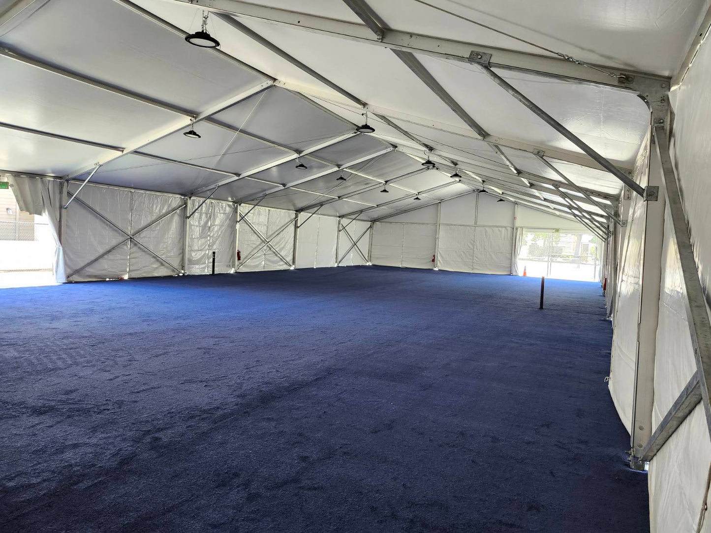 Spacious white outdoor tent with blue carpet flooring, ideal for events and gatherings.