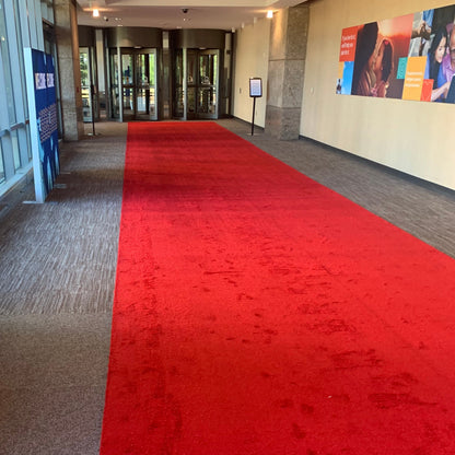 Bright red carpet runner in an indoor corridor, perfect for events and ceremonies.