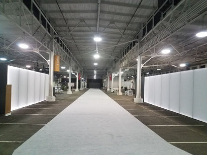 Spacious event venue with white walls, gray carpet, and bright overhead lights for exhibitions.