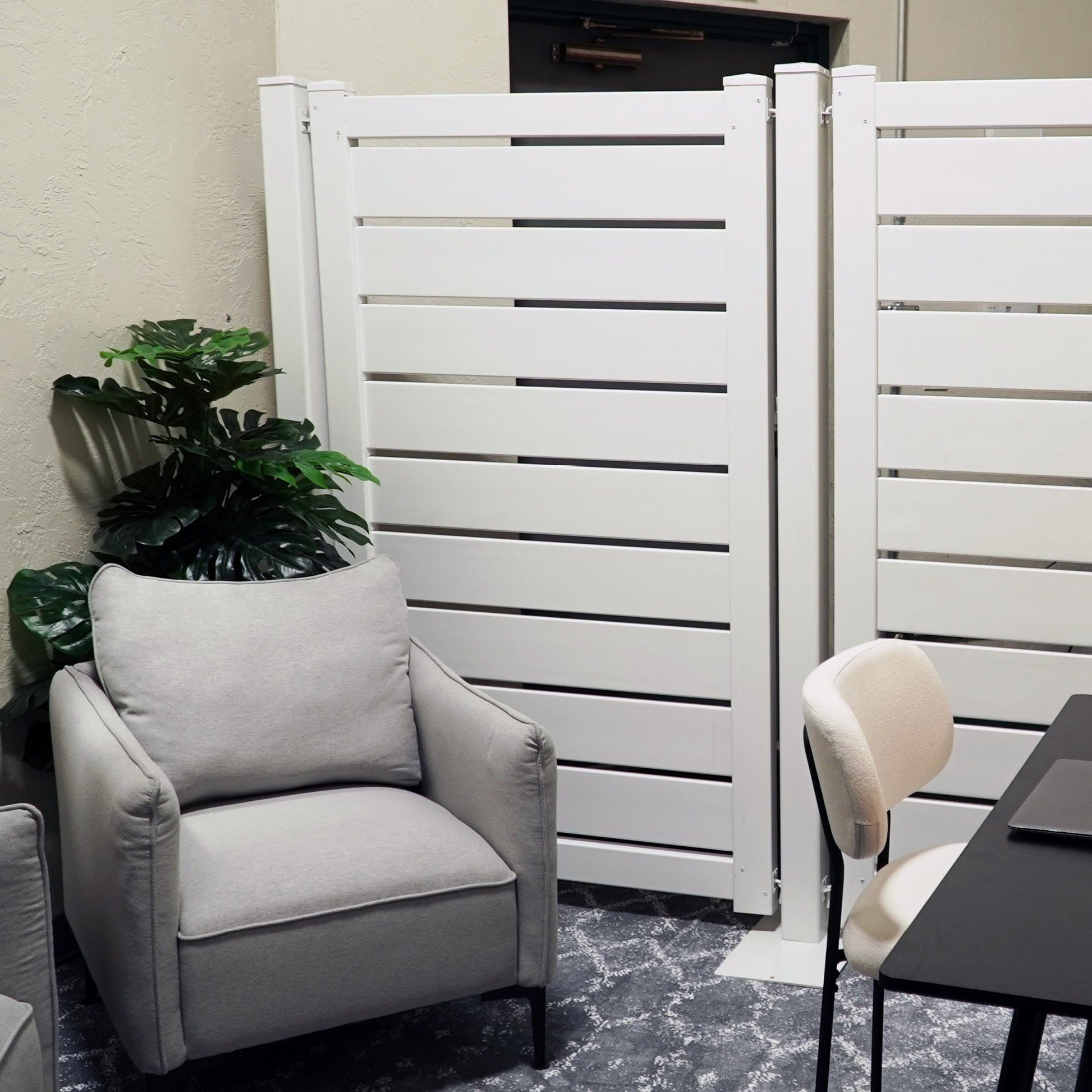 Modern white privacy screen with slats, set in a stylish indoor space featuring a gray armchair.