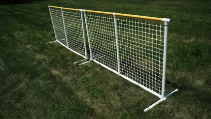 Durable white soccer goal with yellow top rail, ideal for outdoor play on grass, sturdy netting.