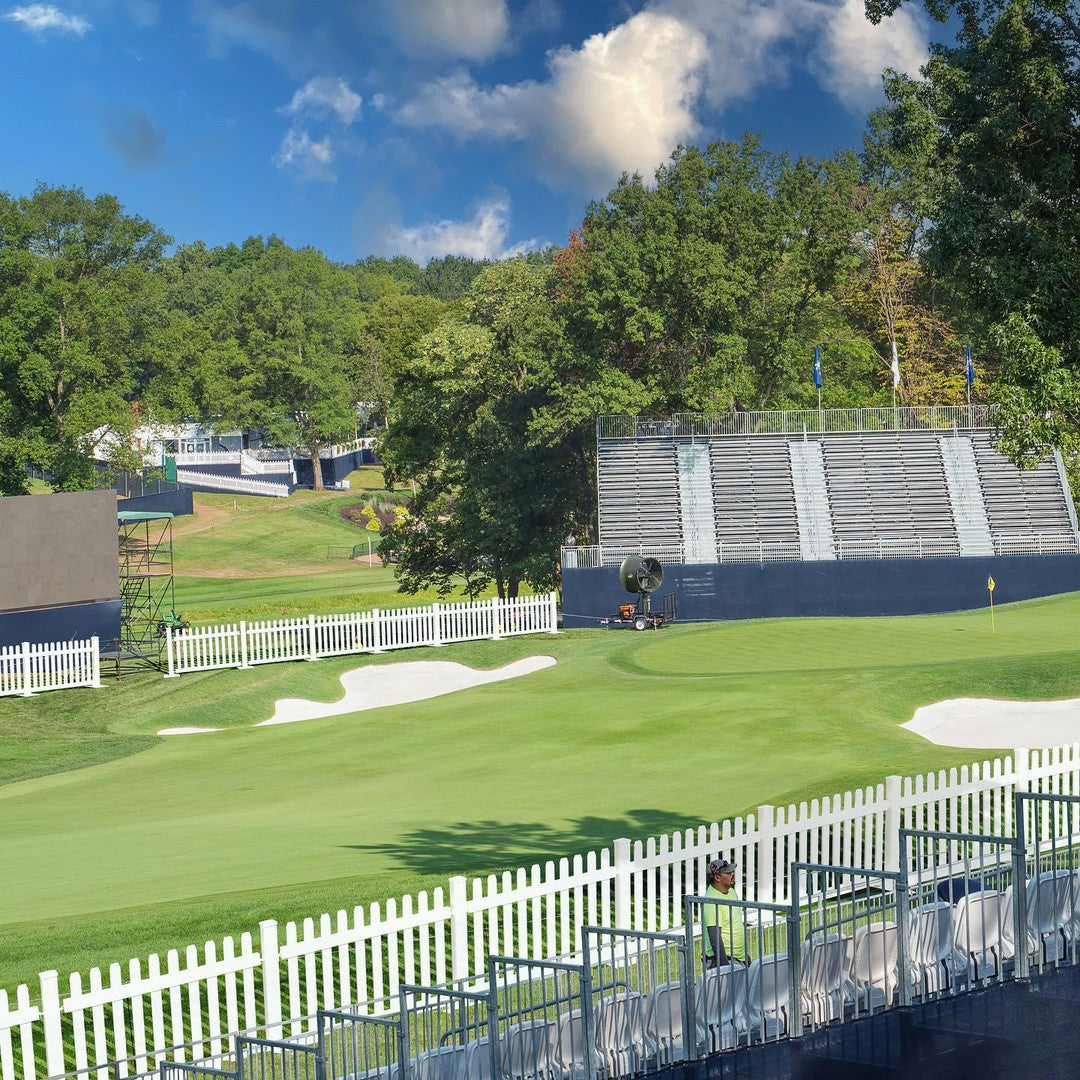 Scenic golf course view with lush green grass, white sand traps, and bleacher seating.