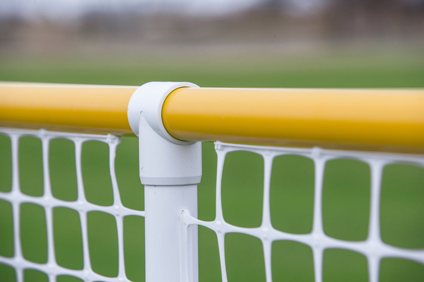 Close-up of a yellow sports goal post connector, featuring durable plastic and netting for enhanced play.